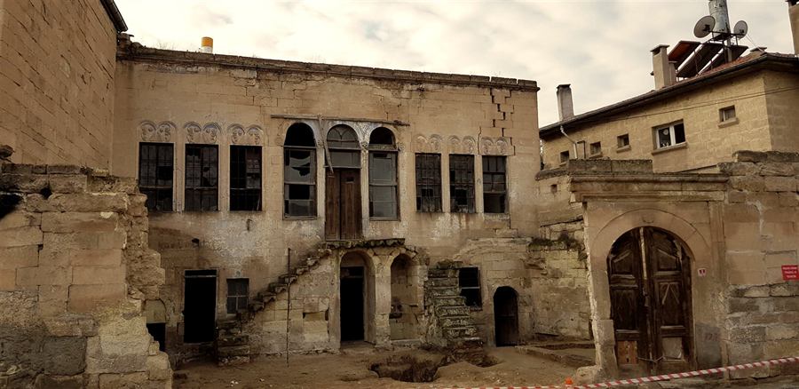 The mansion's facade before restoration, with broken windows and a cracked wall
